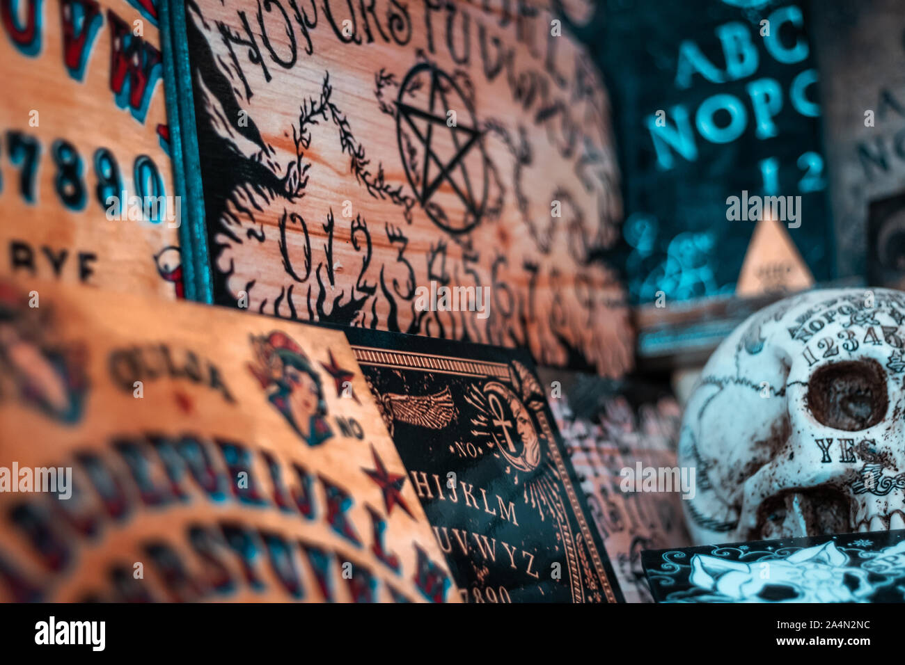 Talking board and planchette, also known as the Ouija board, used for communicating with the dead and other spirits. Halloween background. White skull. Stock Photo