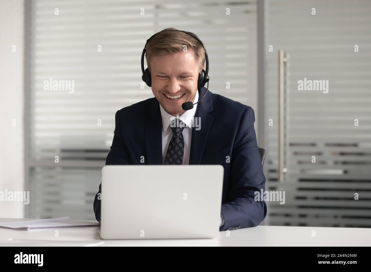 Happy smiling businessman in headset using laptop, working online Stock Photo