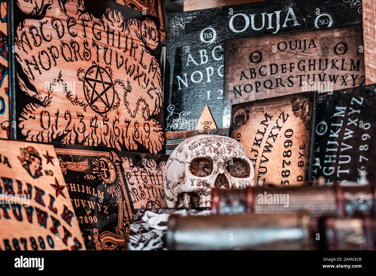 Talking board and planchette, also known as the Ouija board, used for communicating with the dead and other spirits. Halloween background. White skull. Stock Photo