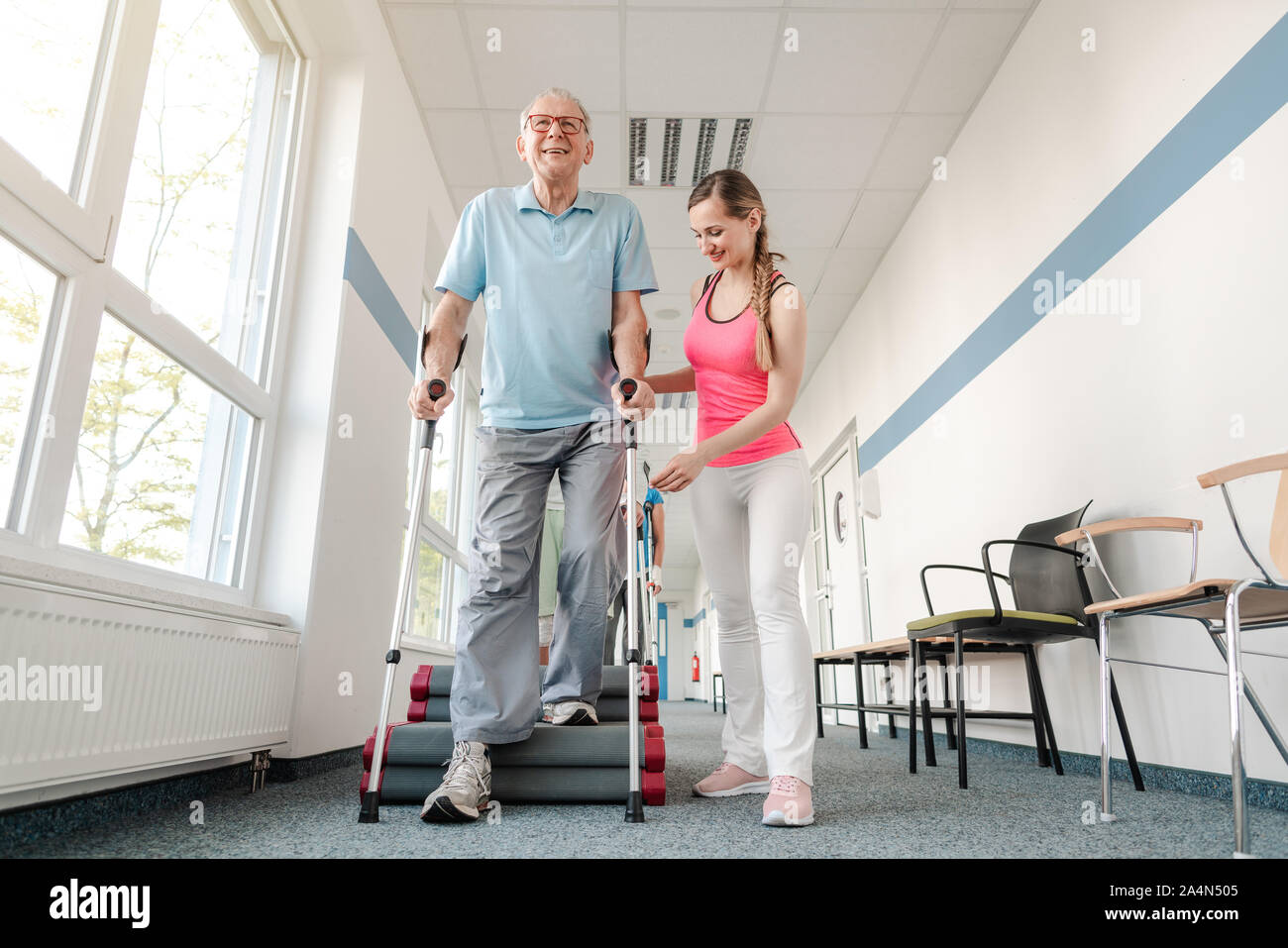 Seniors in rehabilitation learning how to walk with crutches Stock