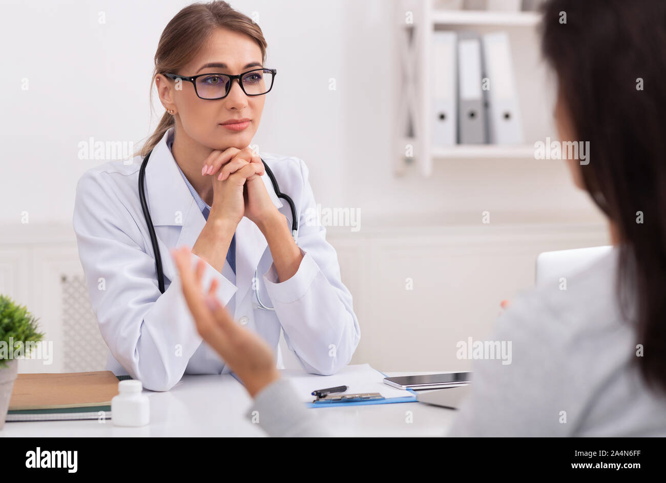 Lady Doctor Listening To Patient Complaining About Health In Office Stock Photo