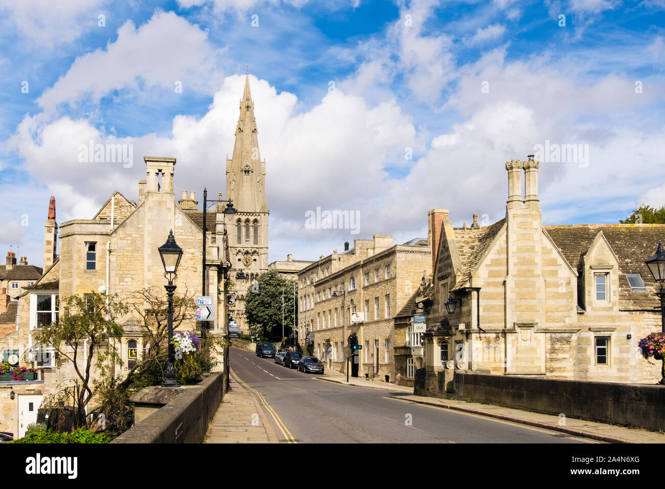 View along a street lined with old limestone buildings to St Mary's church from bridge over River Welland. Stamford, Lincolnshire, England, UK Stock Photo