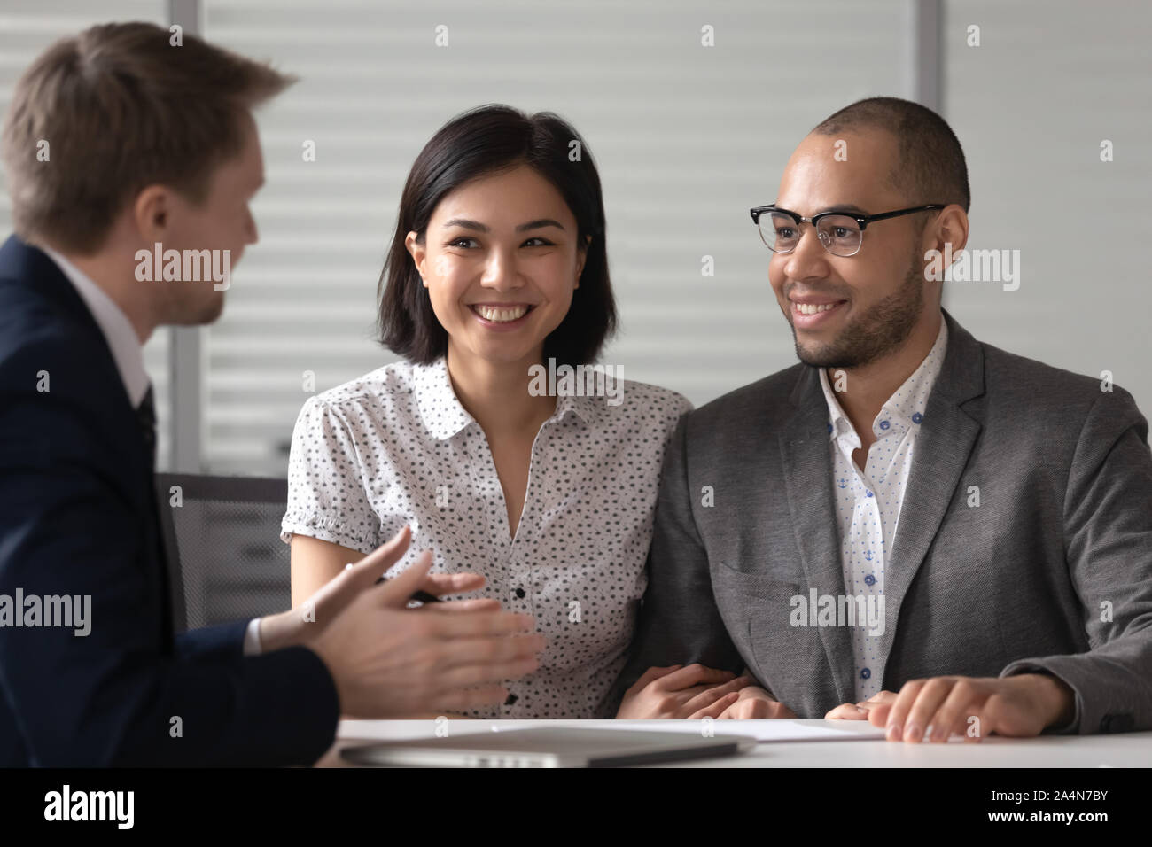 Manager realtor banker consulting happy diverse young couple at meeting Stock Photo