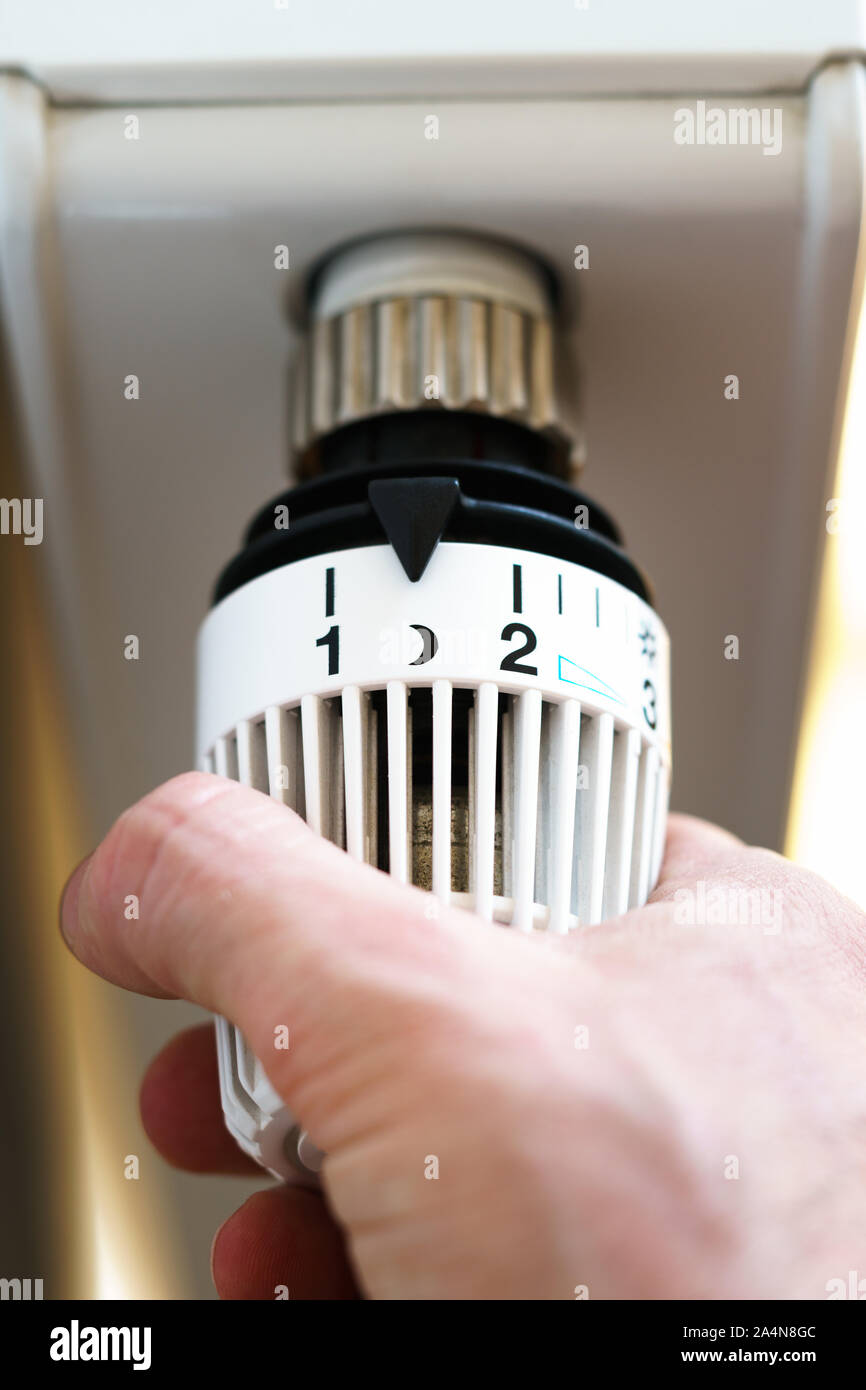 Hand of man adjusting radiator thermostat valve down to moon (night