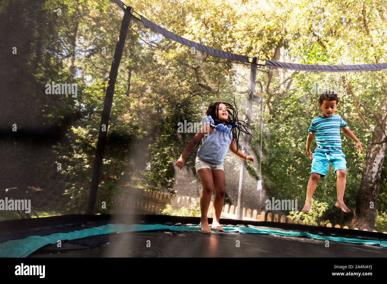 Boy and girl jumping on trampoline Stock Photo - Alamy