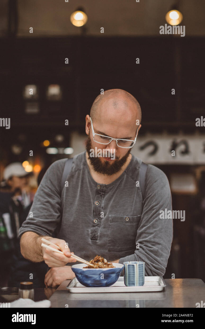 Young man eating asian dish Stock Photo