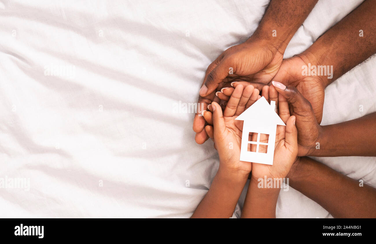 Black family of three holding paper house figure in hands Stock Photo