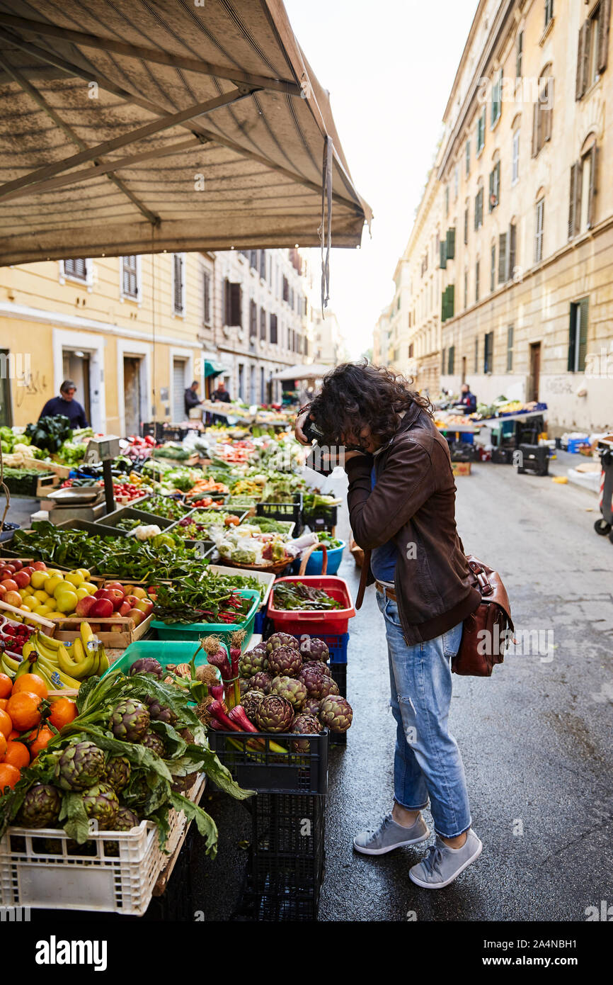 Woman taking photos of vegetables on stall Stock Photo