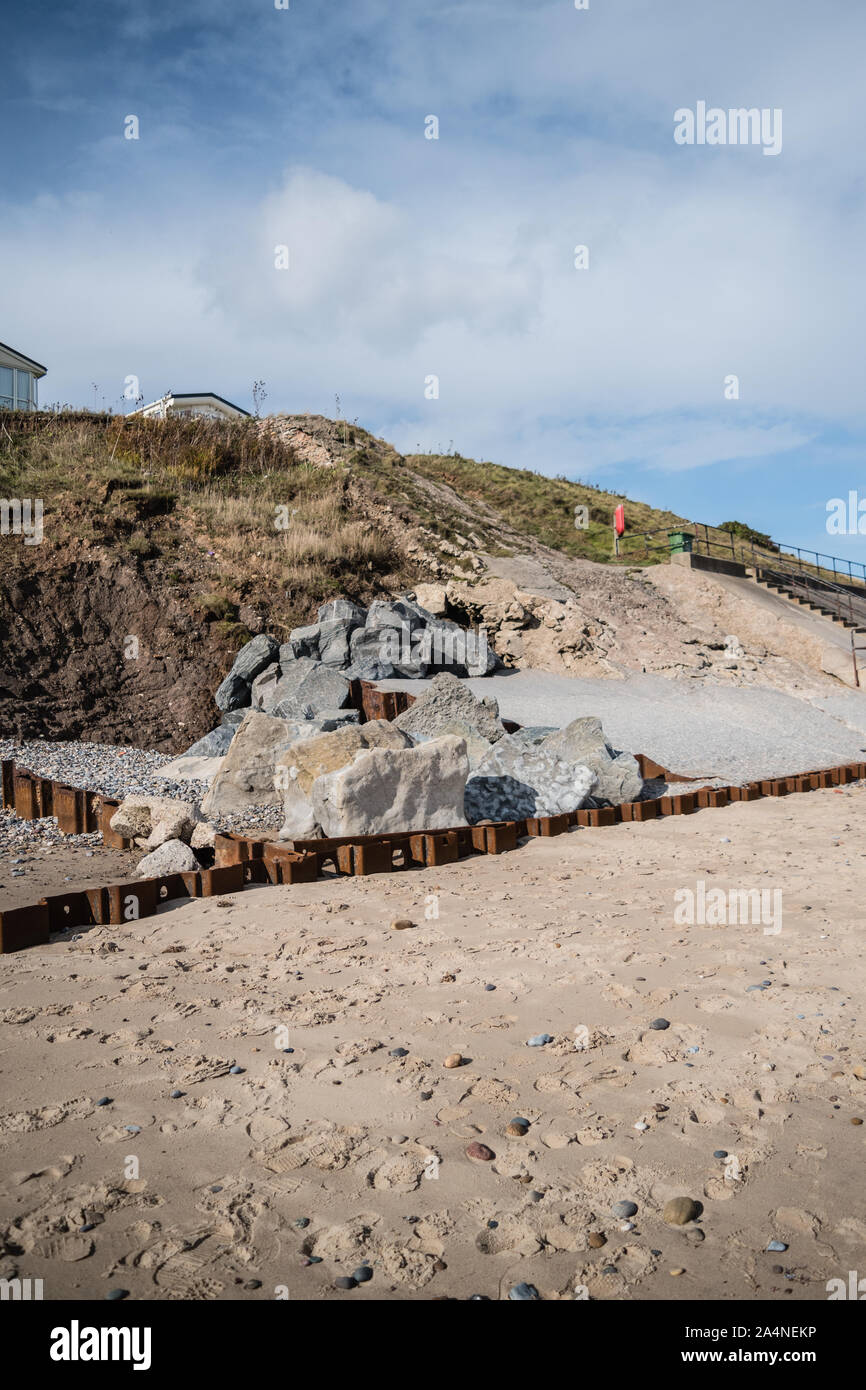 A view of Hornsea Beach and caravan park on cliff edge with examples of coastal protection on the beach Stock Photo