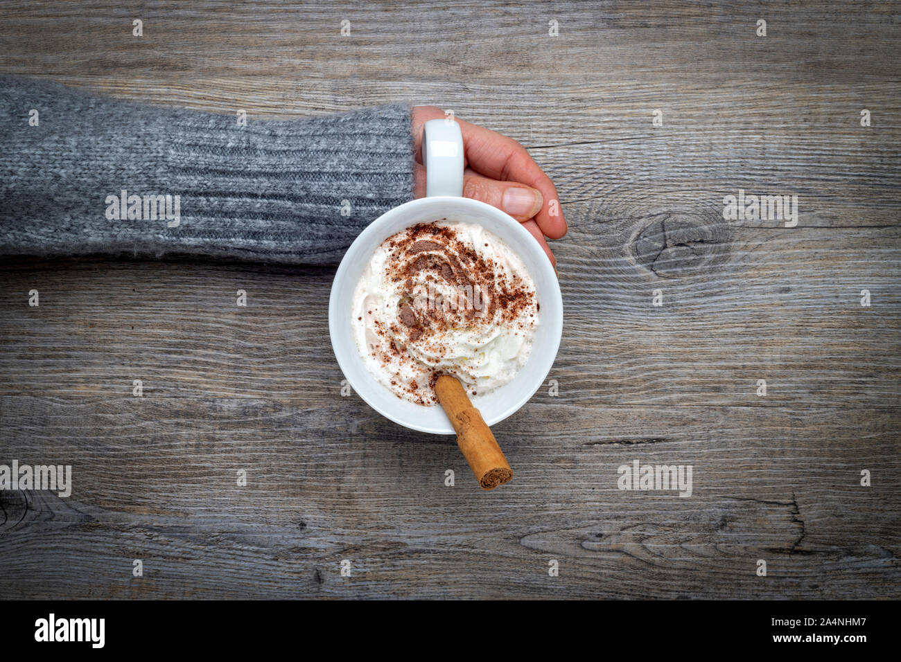 woman wearing a warm jumper holding a mug of hot chocolate, from above. Stock Photo