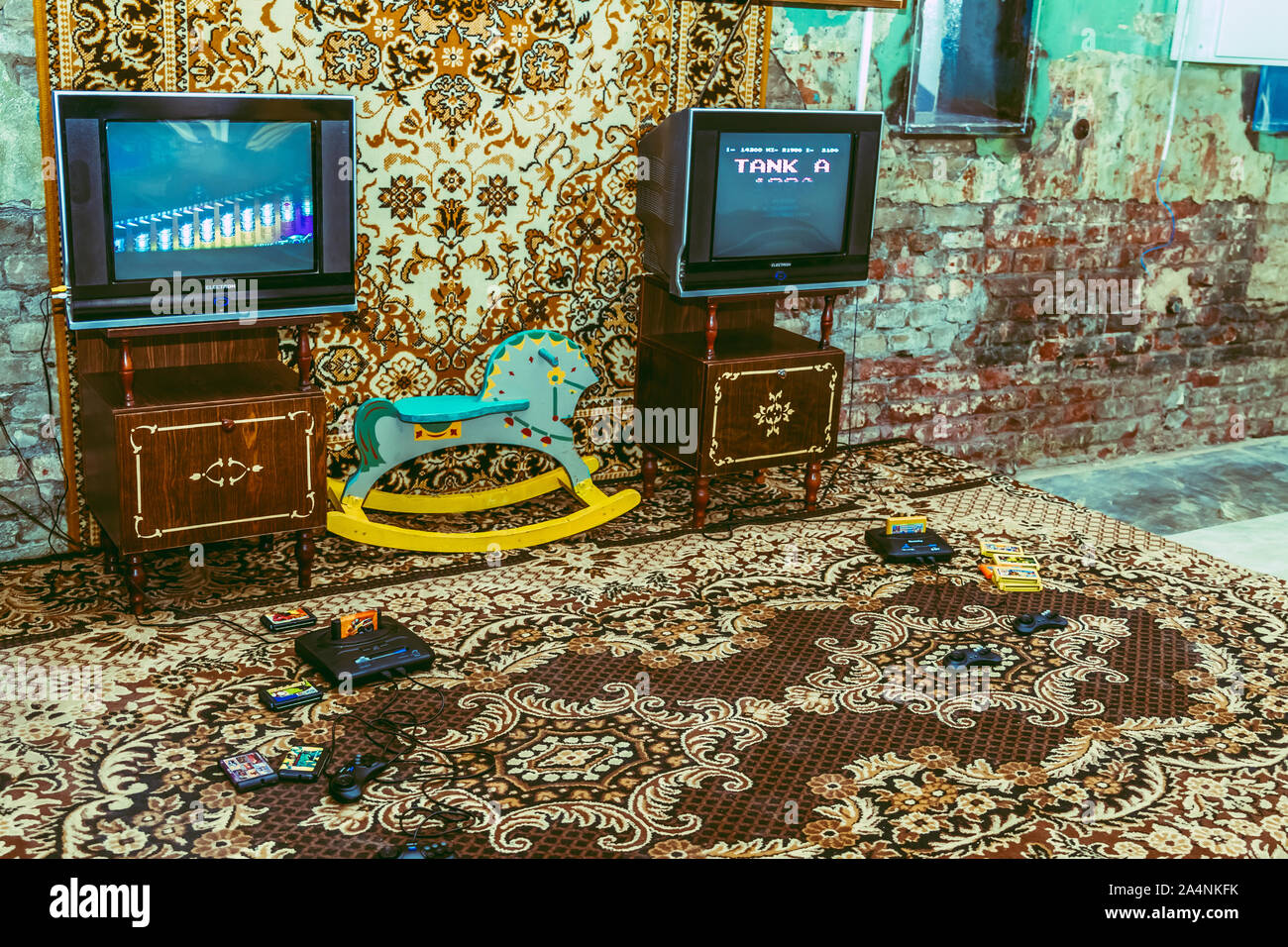 KHARKIV, UKRAINE MAY 28, 2017: Vintage room, old-fashioned carpet, retro TV, sega, game console, 90s collectible bottles and standard wooden cabinet. Stock Photo
