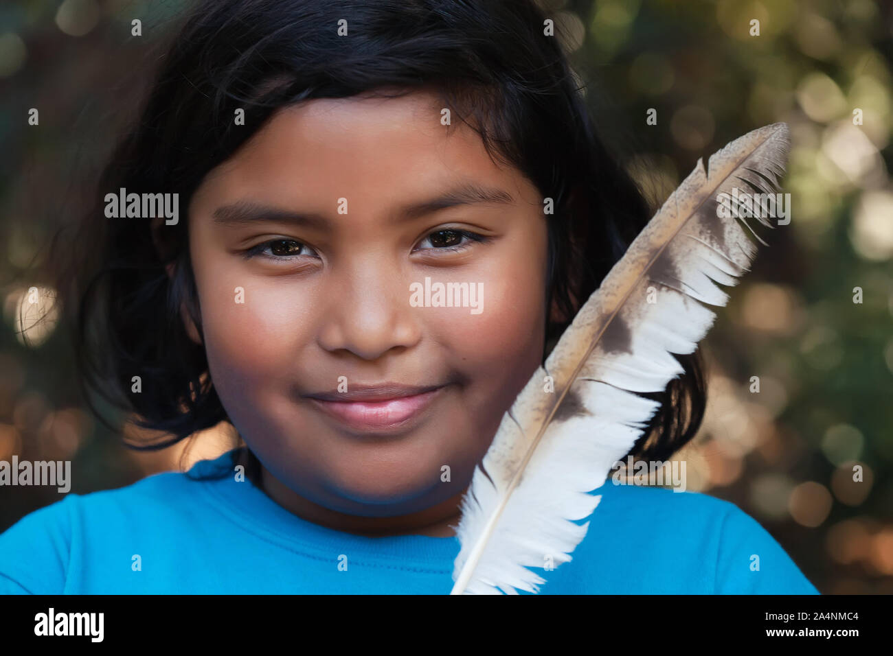 A beautiful little girl holding a spiritual feather; a symbol of flight and freedom. Stock Photo