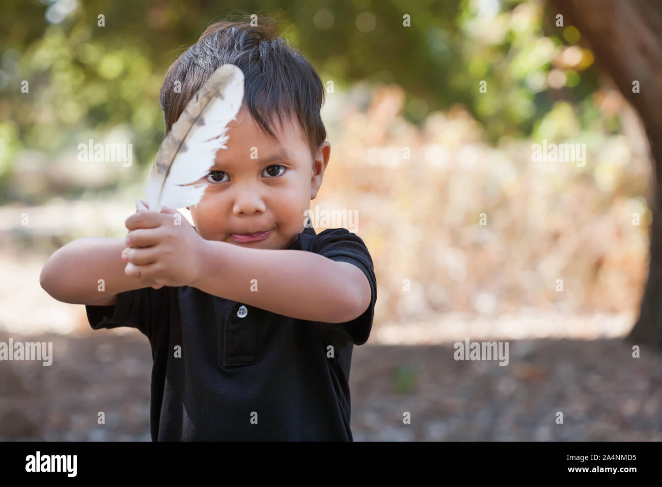 A little boy holding a birds feather like a sword in a crown guard position. Stock Photo