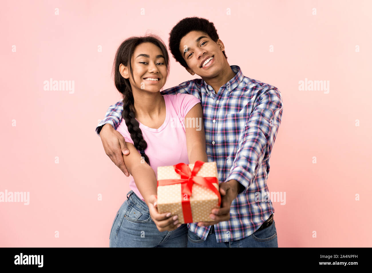 Happy young couple stretching present box to camera Stock Photo