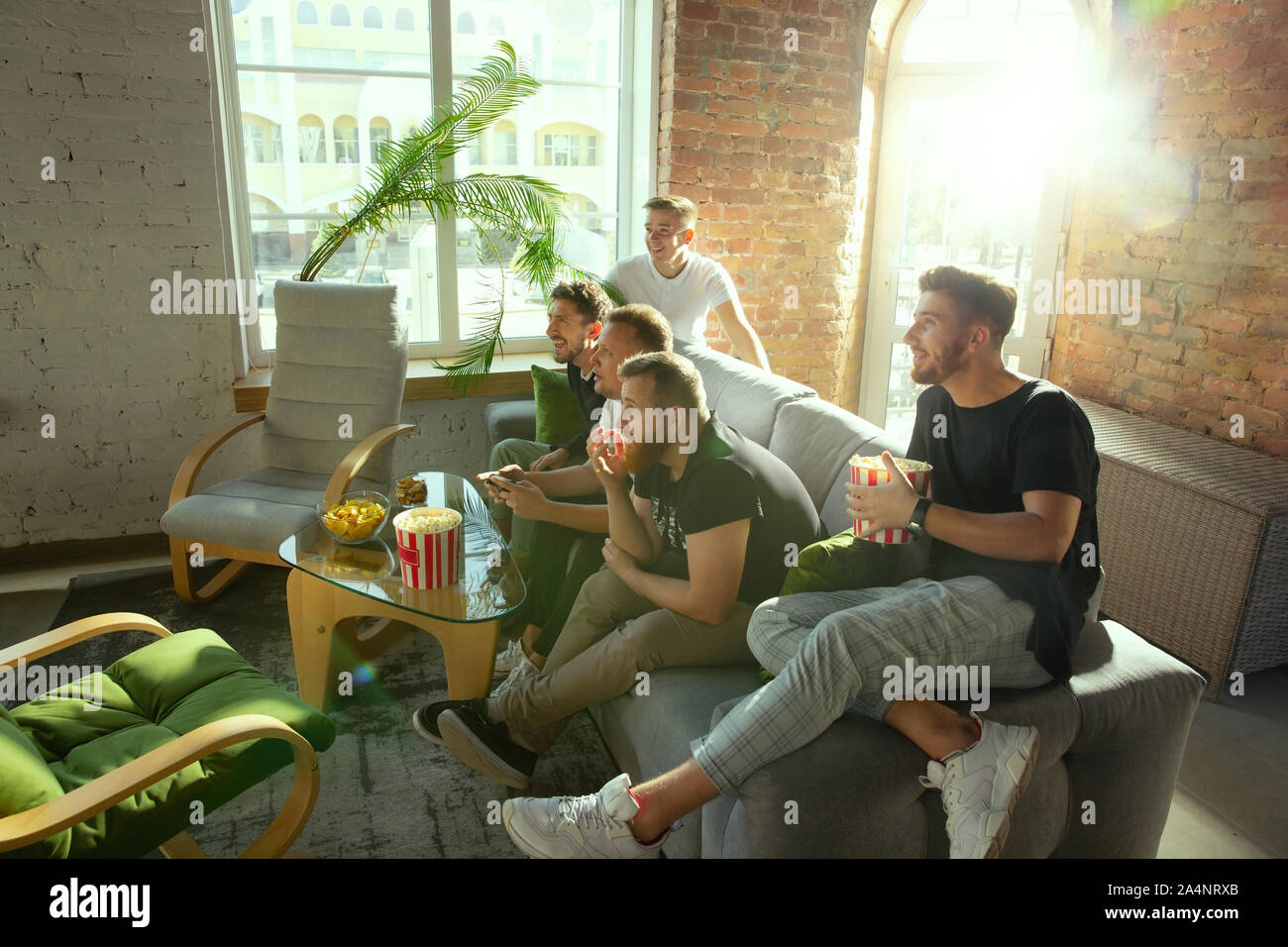 Excited multiethnic teen friends enjoying video games, free time at home, Stock image