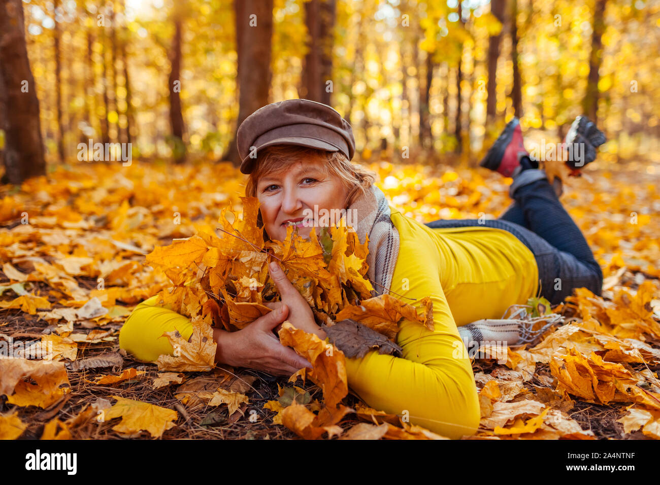fall-activities-woman-lying-on-heap-of-leaves-in-autumn-park-senior-woman-having-fun-outdoors-2A4NTNF.jpg