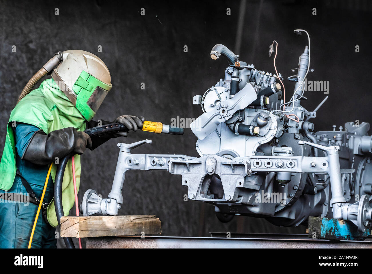 Sandblasting. Enthusiastic restorer blasting chassis and engine body of