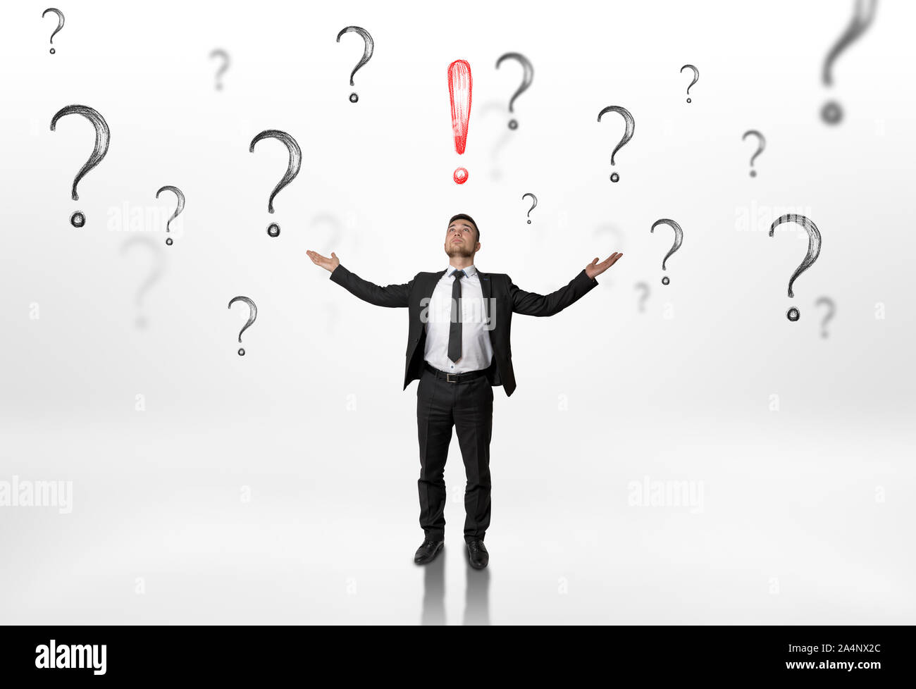 Businessman stands with raised hands looking upwards at an exclamation