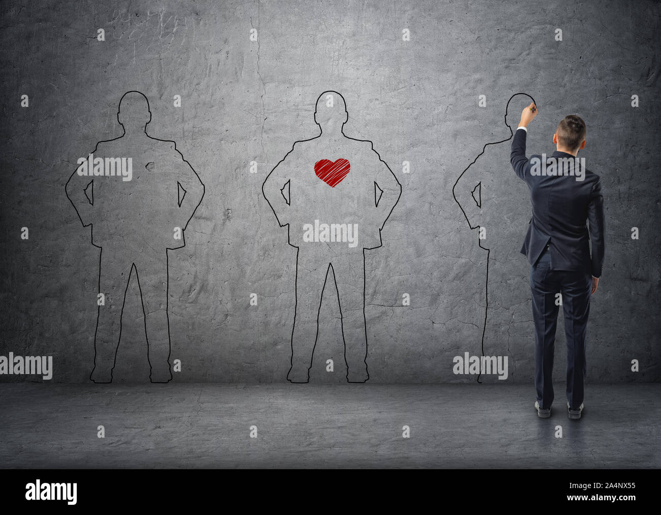 Back view of a businessman drawing men's silhouettes on concrete wall. The middle one with red heart in its chest. Stock Photo