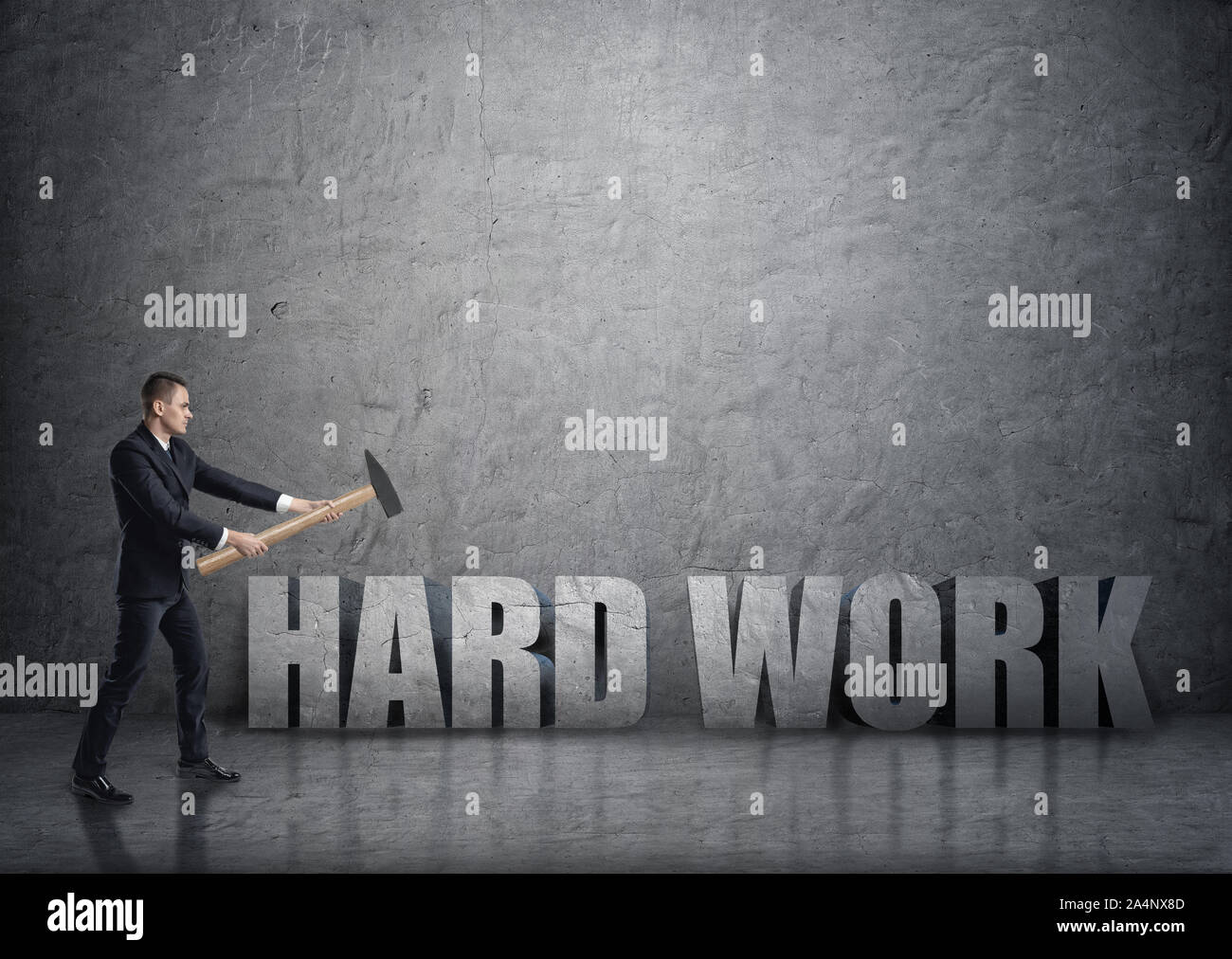 Side view of young businessman crashing 3D concrete 'hard work' words with a hammer Stock Photo