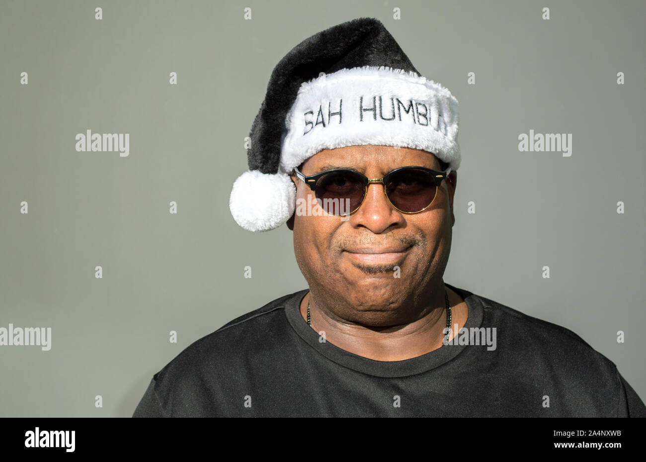 cranky African American man wearing a black and white Bah Humbug hat with a pom pom against a solid background Stock Photo