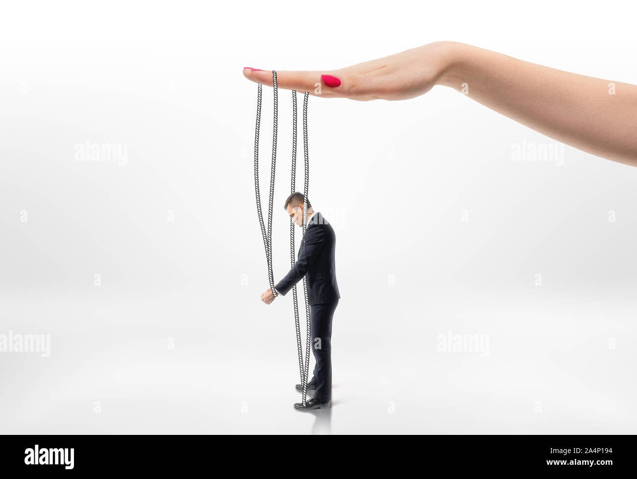 Hand pulling businessman by strings. Stock Photo
