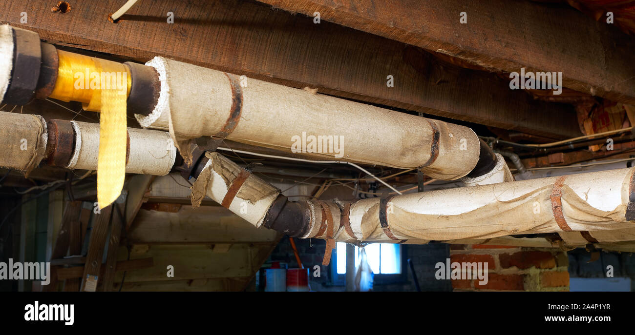 Basement plumbing pipes wrapped with asbestos insulation Stock Photo