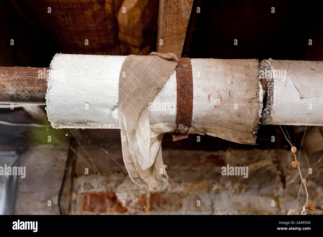 Basement plumbing pipes wrapped with asbestos insulation. Stock Photo