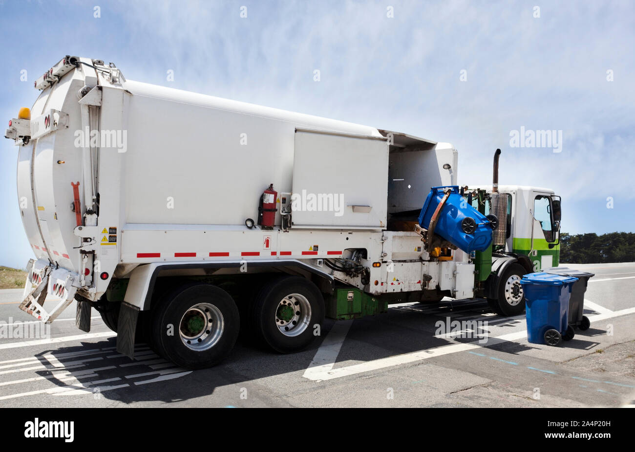 Industrial garbage truck with hydraulic lift arm under blue sky. Rear and side view. Nobody. Stock Photo