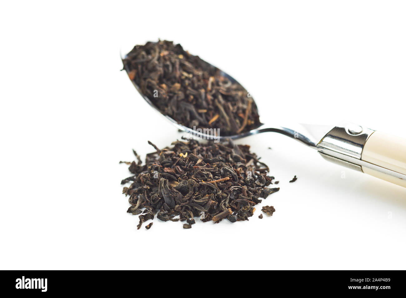 Dried black tea leaves in spoon isolated on white background. Stock Photo