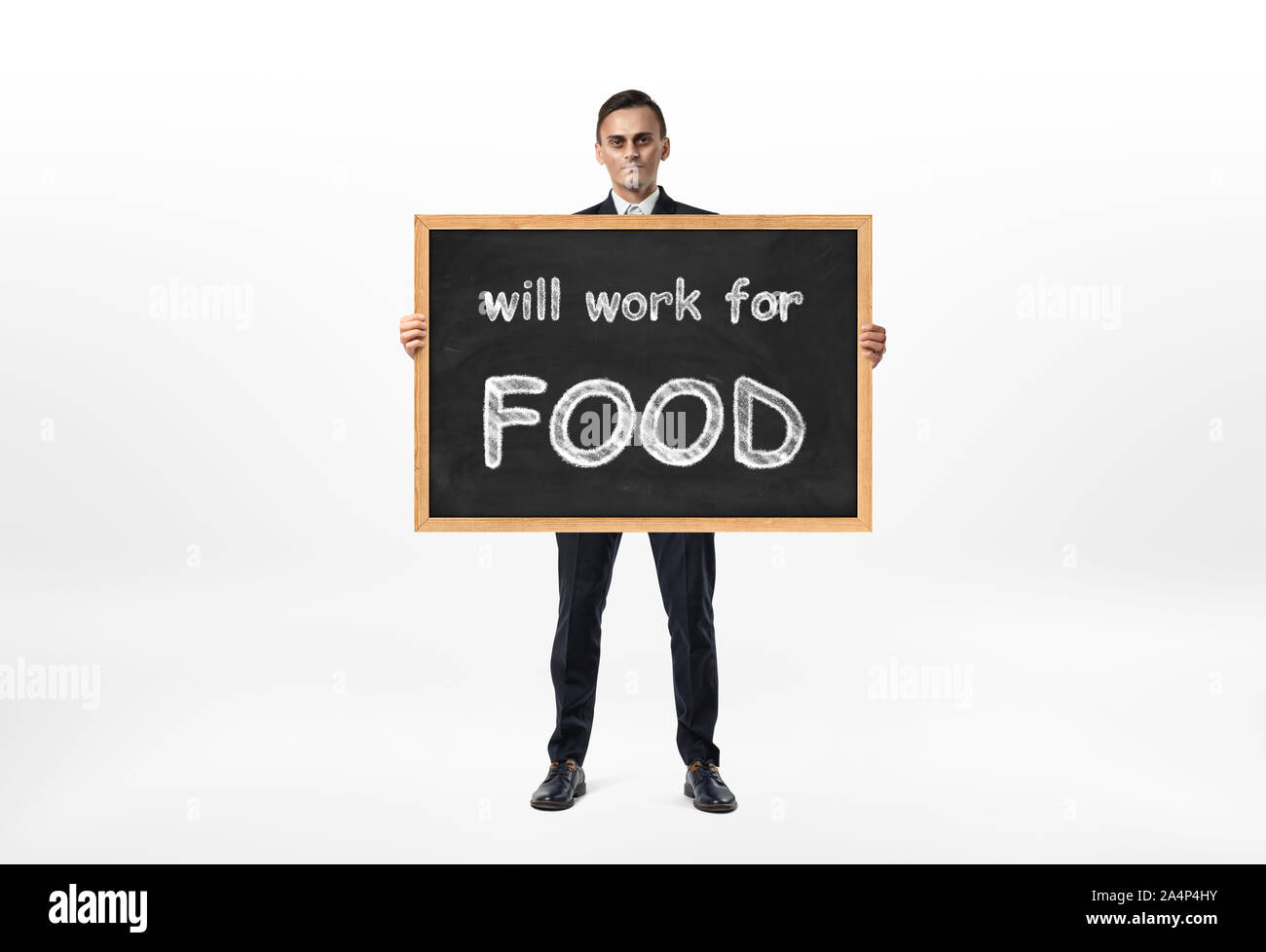 Businessman standing and holding blackboard with words 'will work for food' written on it Stock Photo