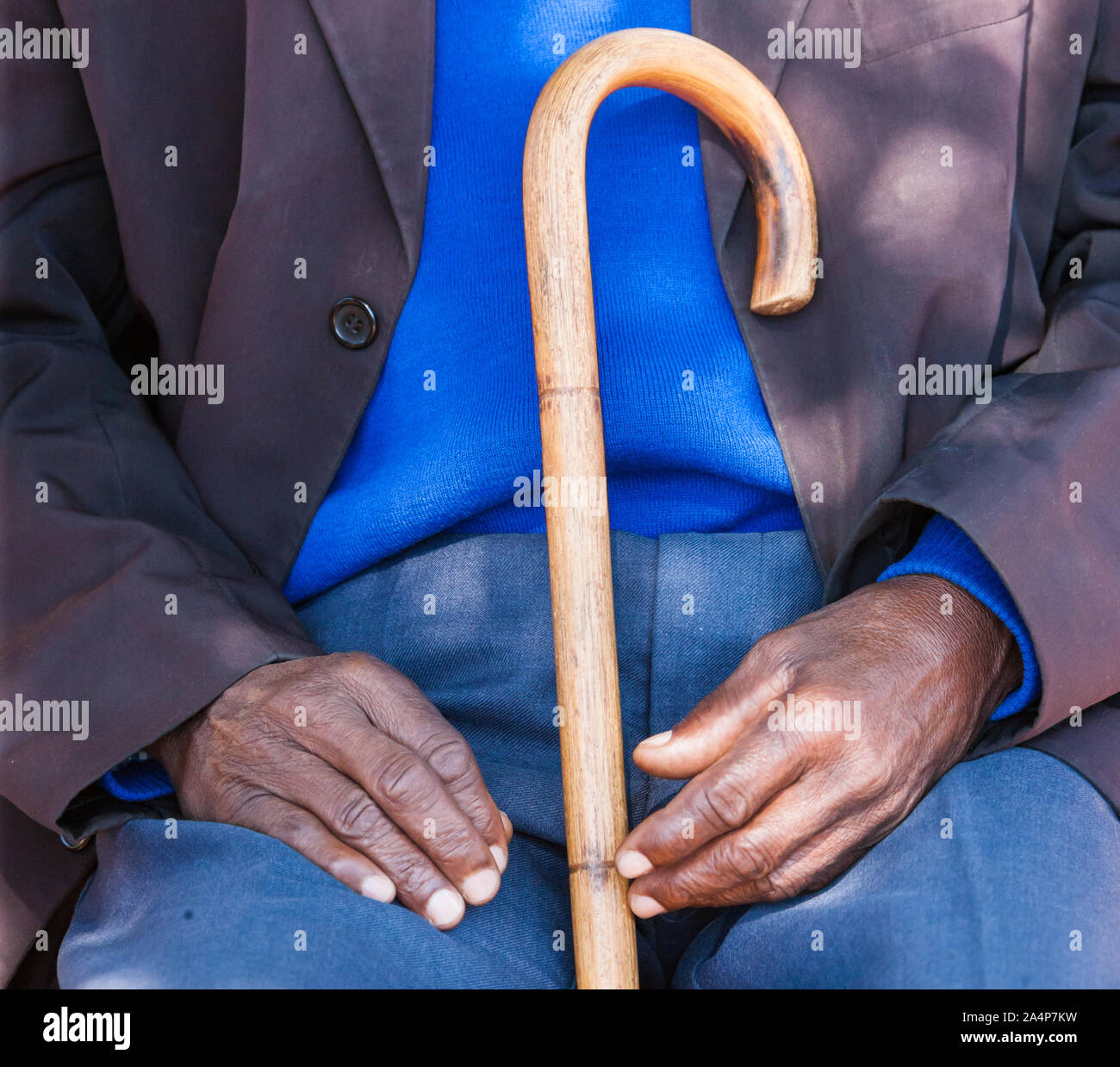 old man sited holding his walking stick Stock Photo
