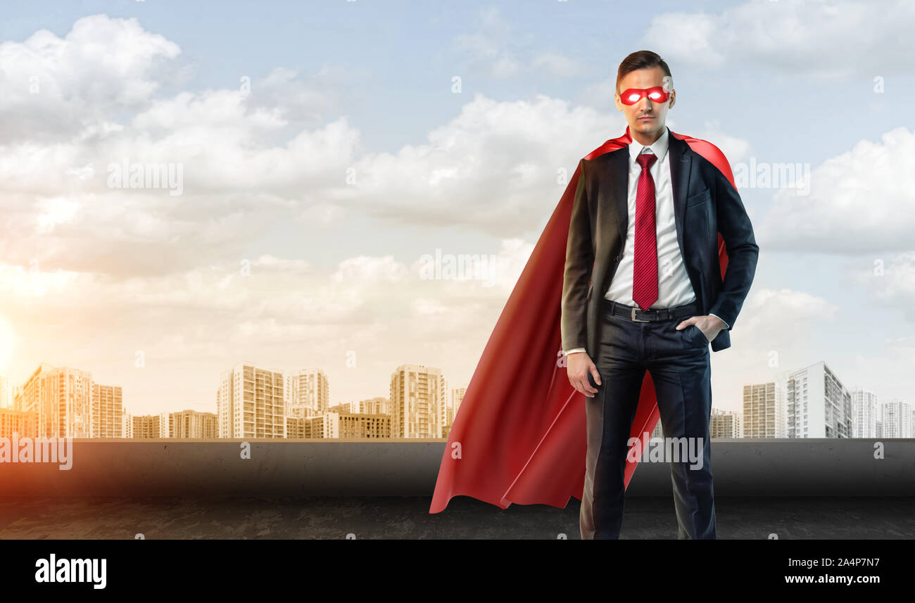 A businessman in superhero mask and cape on the sky background with ...