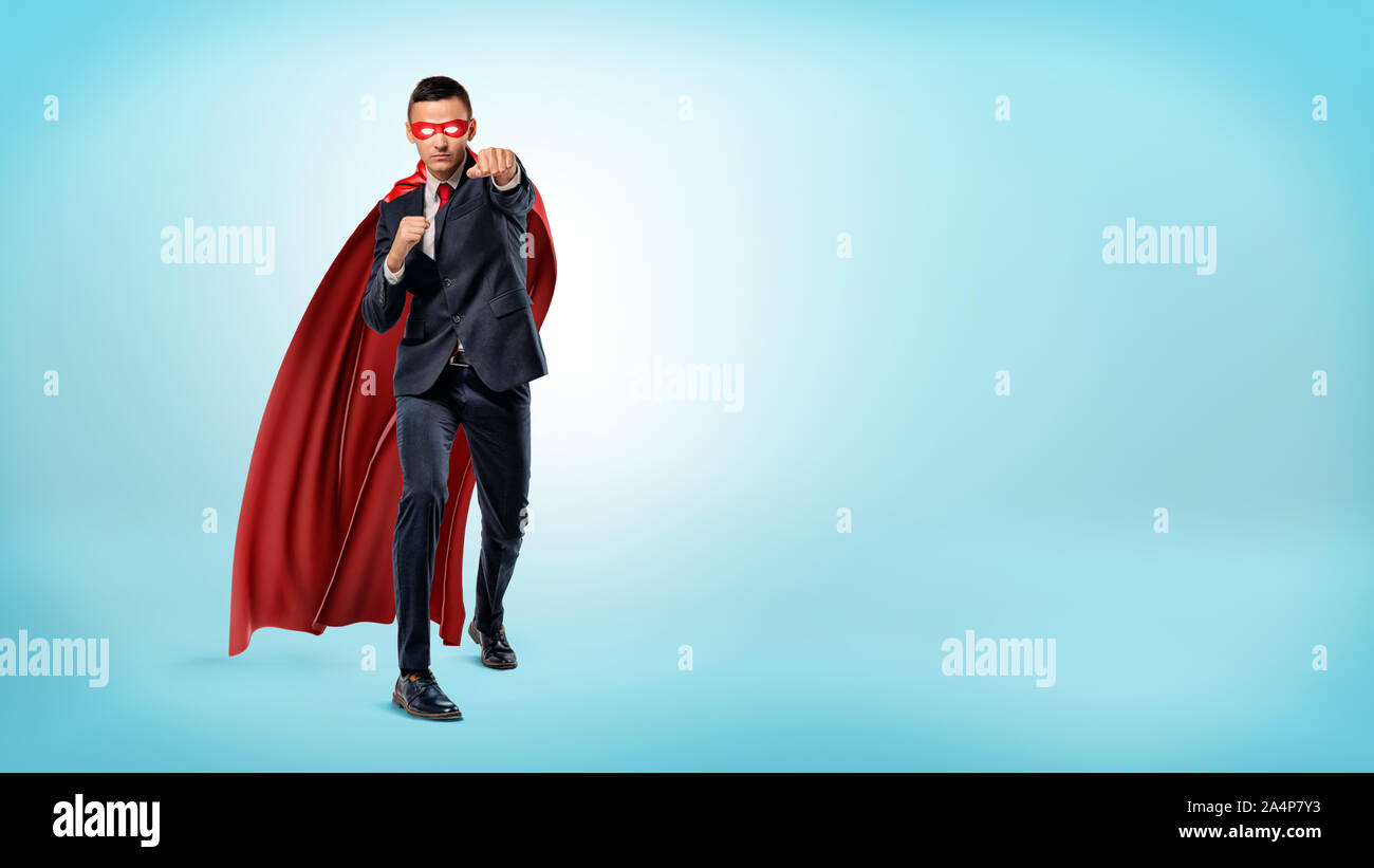 A Businessman In A Flowing Red Superhero Cape And A Mask Throwing Punches At An Invisible Enemy On Blue Background Stock Photo Alamy A Businessman In A Flowing Red Superhero Cape And A Mask Throwing Punches At An Invisible Enemy On Blue Background Stock Photo Alamy