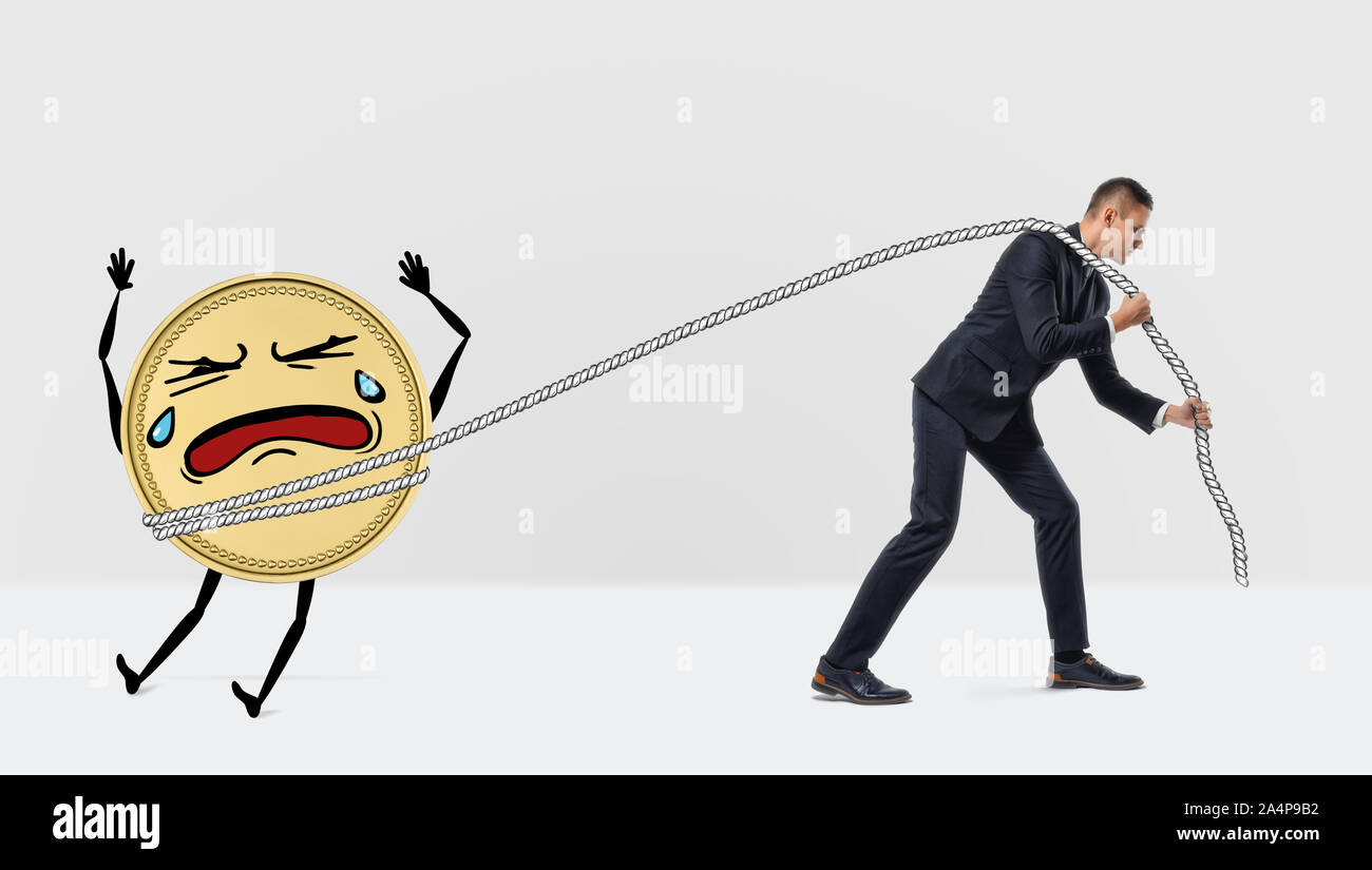 A businessman pulling away an unwilling and crying large golden coin with a rope. Stock Photo