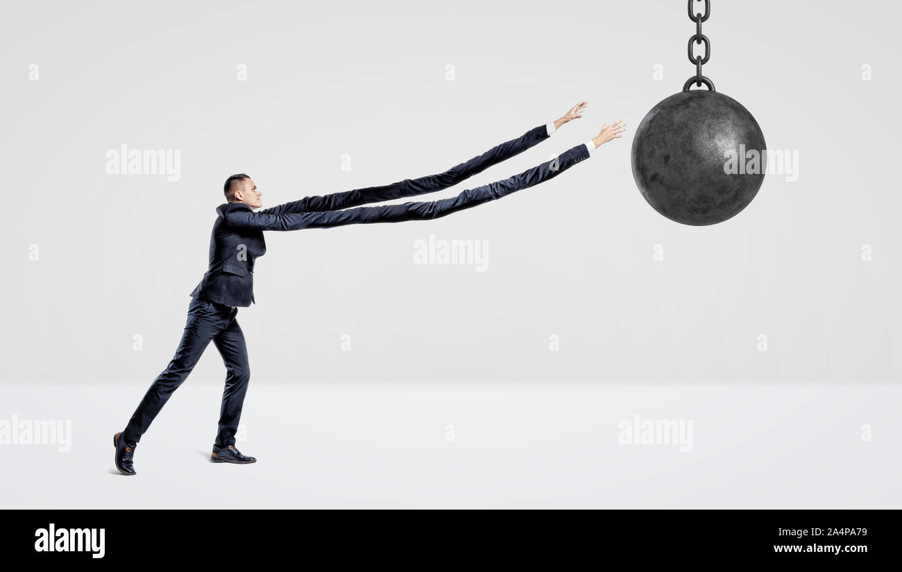 A businessman on white background trying to grab a wrecking ball with his extremely long arms. Stock Photo