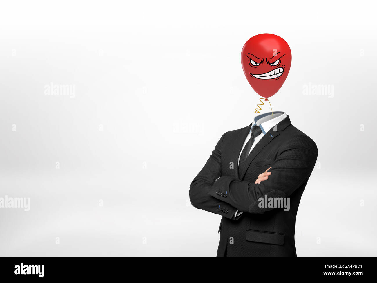 A businessman on white background stands with crossed hands and a red angry face balloon instead of his head. Stock Photo