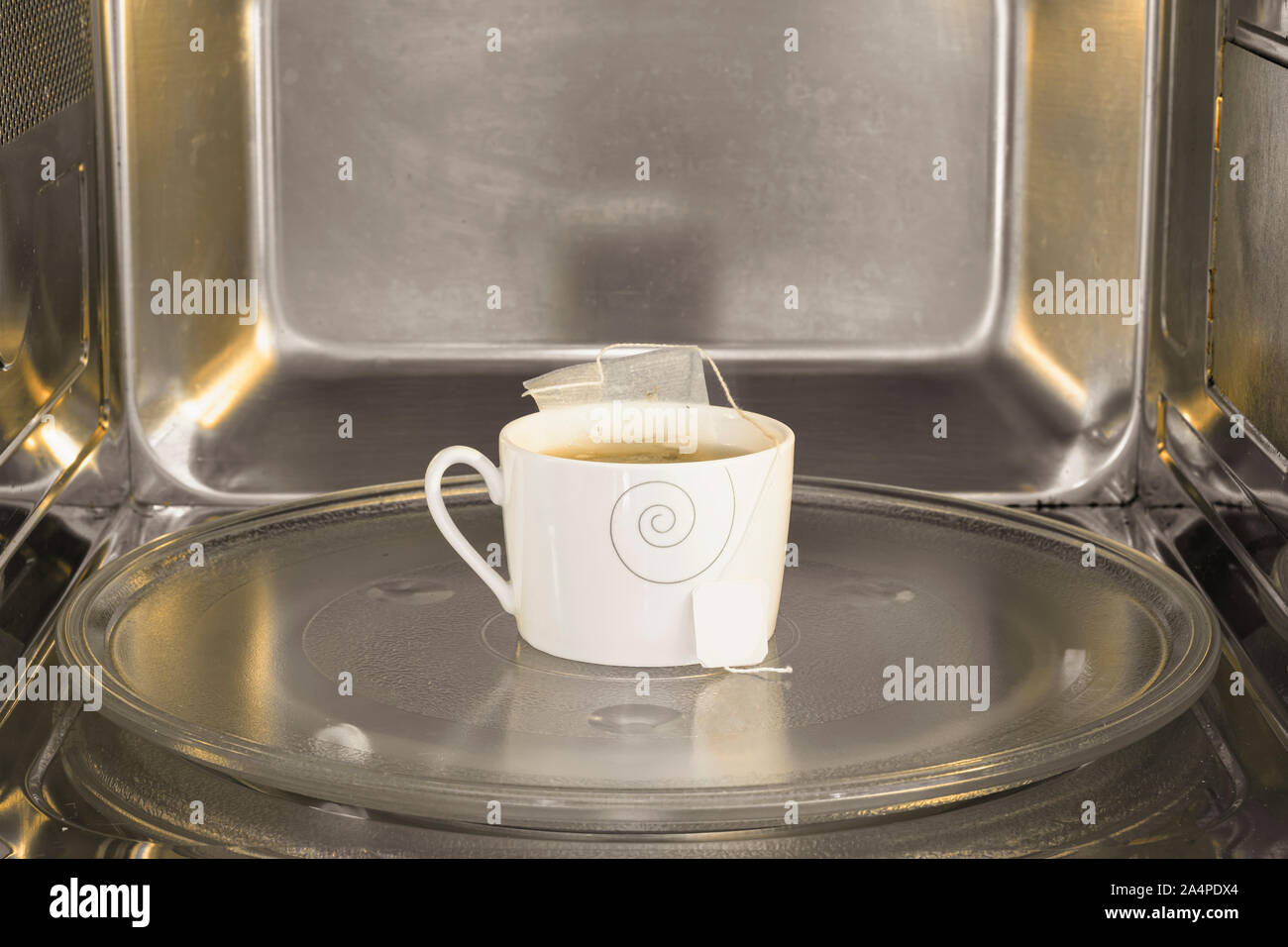 Tea cup inside the microwave. Warming the tea on the microwave. Stock Photo