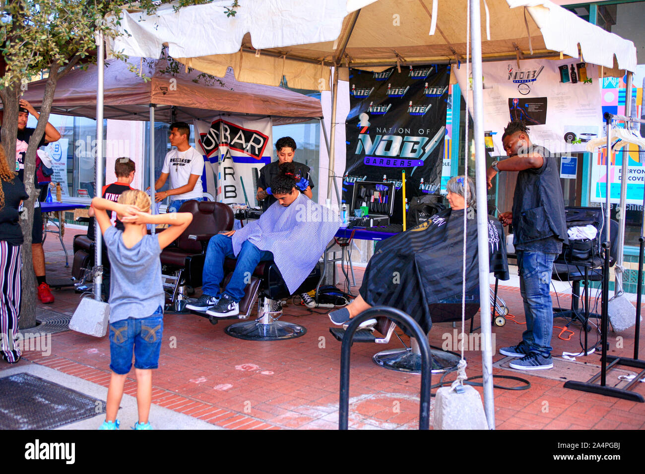 People getting a hair cut or trim at an openair salon at the Tucson