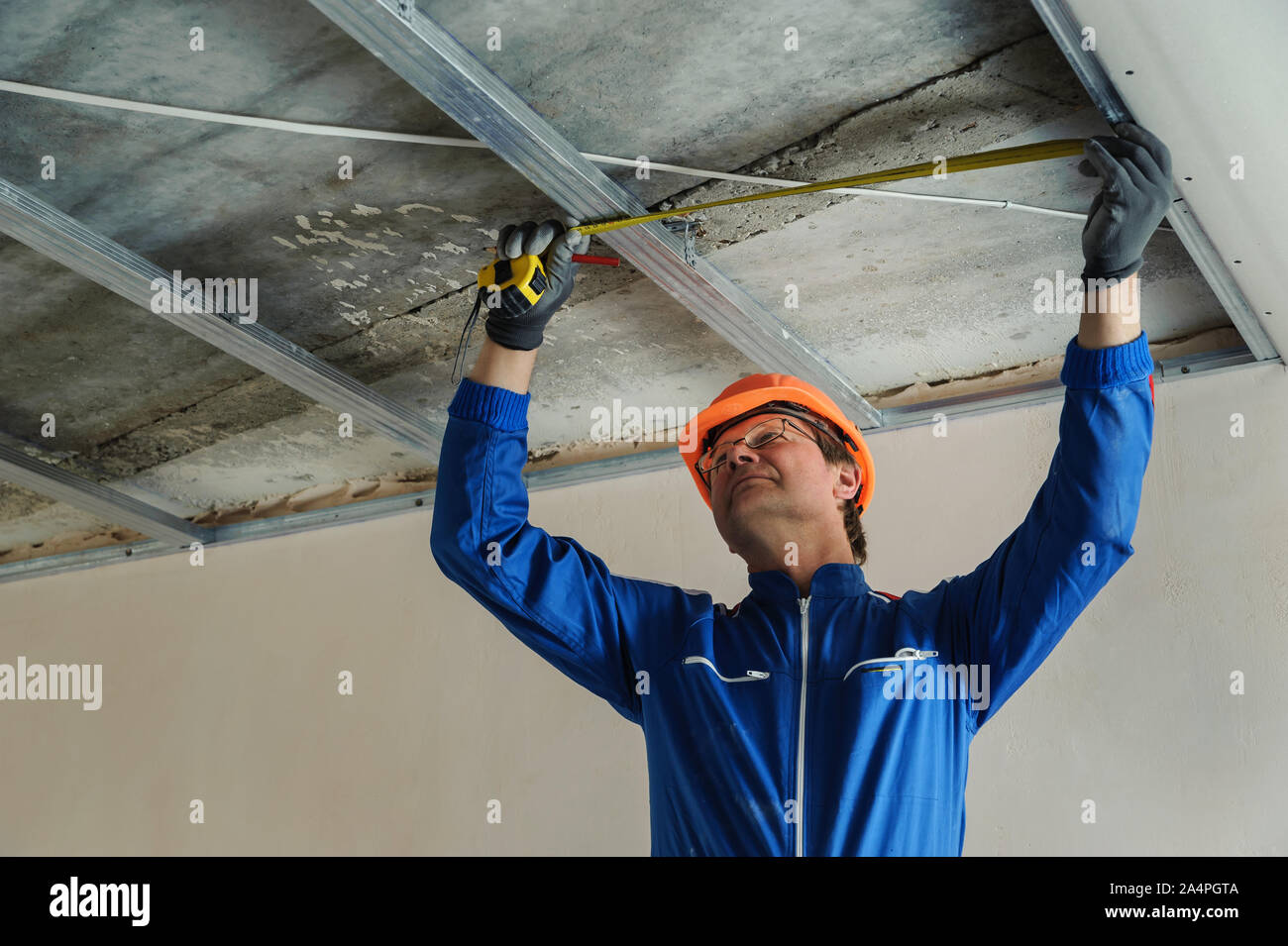 Worker measure metal frame for plasterboard ceilings Stock Photo Alamy