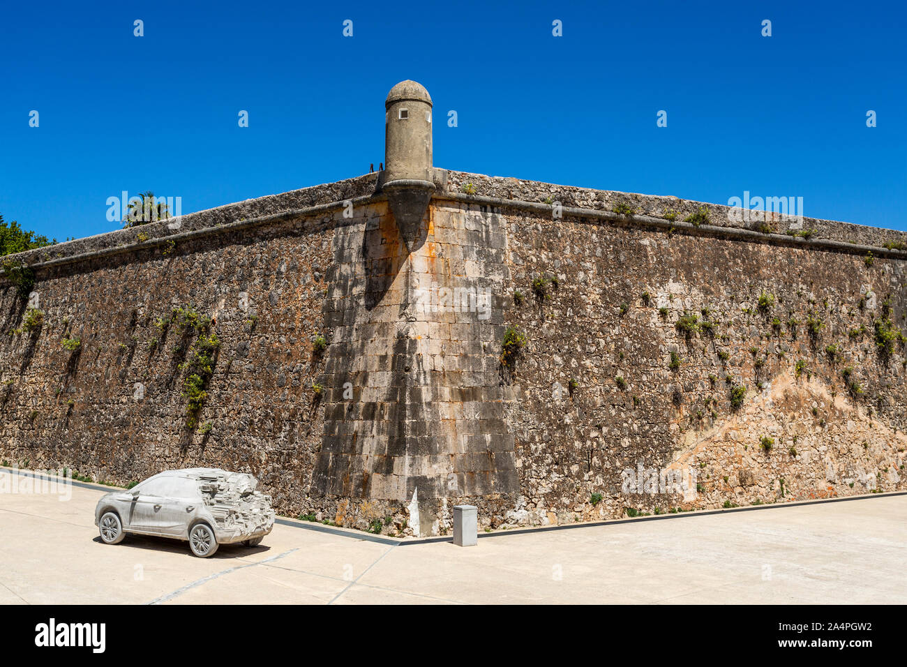 View of the old rampart wall and watchtower of the 16th century Citadel of  Cascais and a modern car exhibit, in Cascais, Portugal Stock Photo