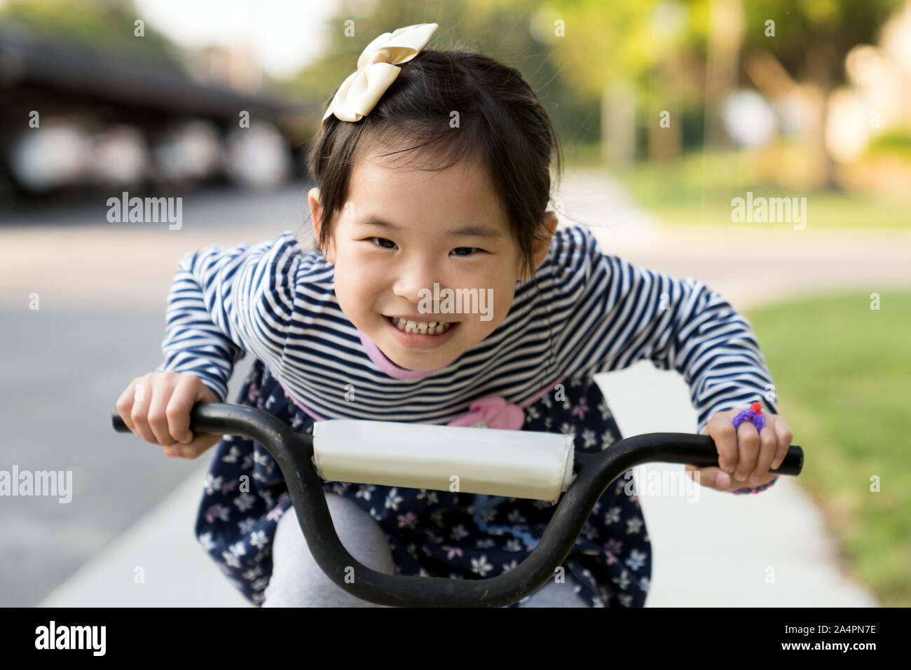 Cute little girl learning ride a bicycle with no helmet Stock Photo Alamy