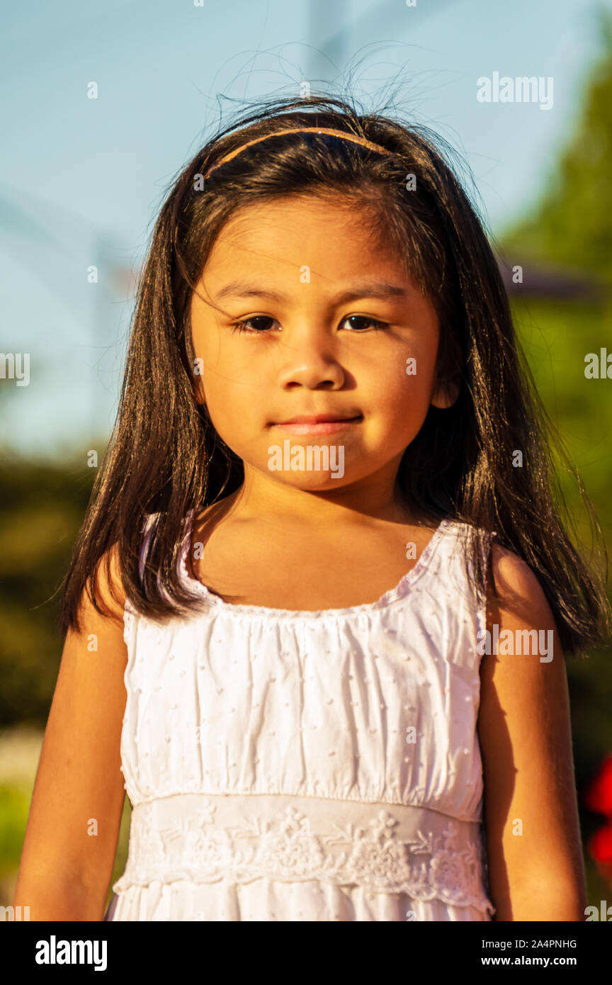 Cute Mexican American children are playing and enjoying bubbles in a garden park. Latino youth having fun together. Stock Photo