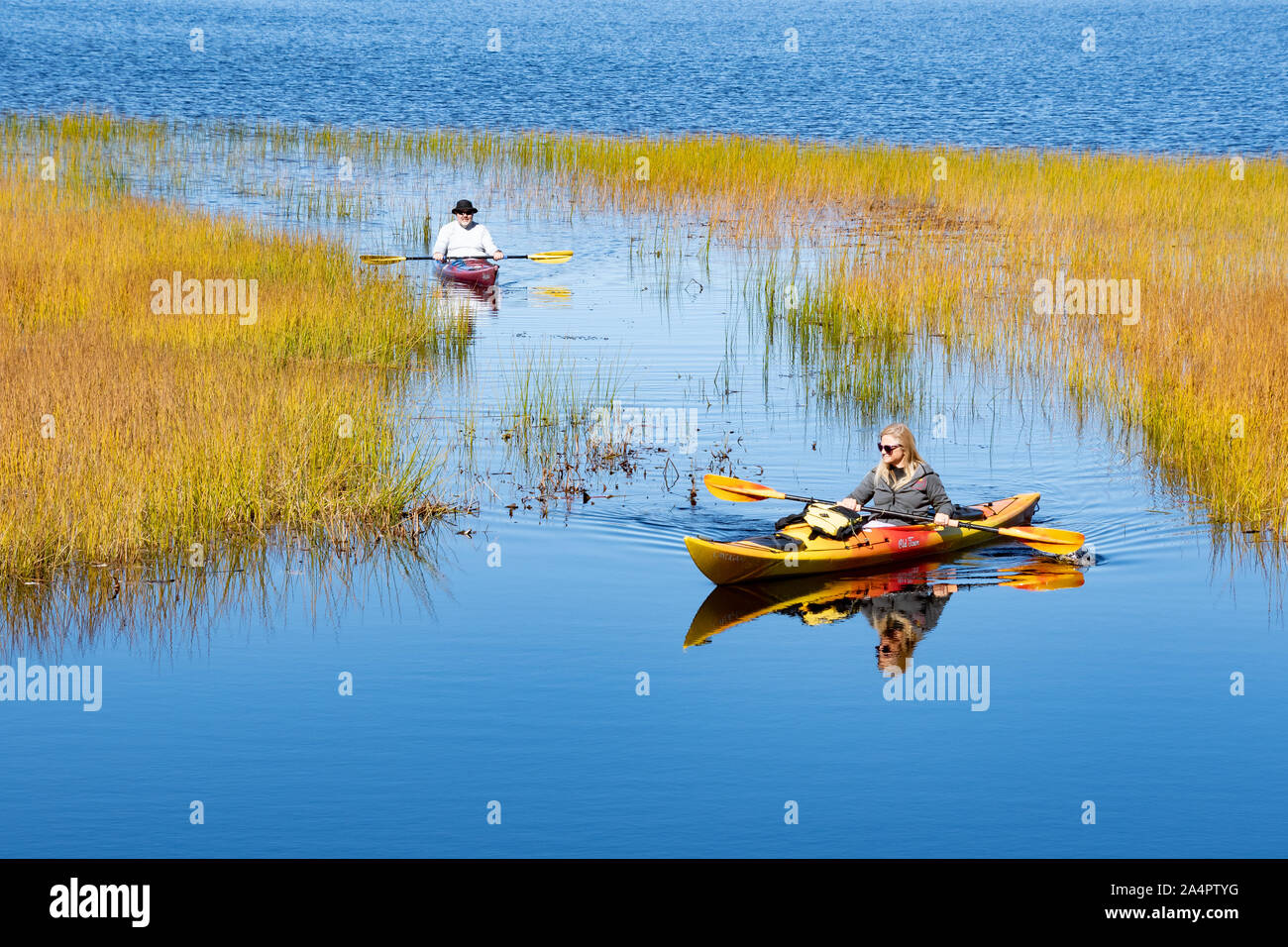 A man and woman paddling kayaks on Lake Pleasant, NY in the Adirondack Mountains on a clear autumn afternoon. Stock Photo