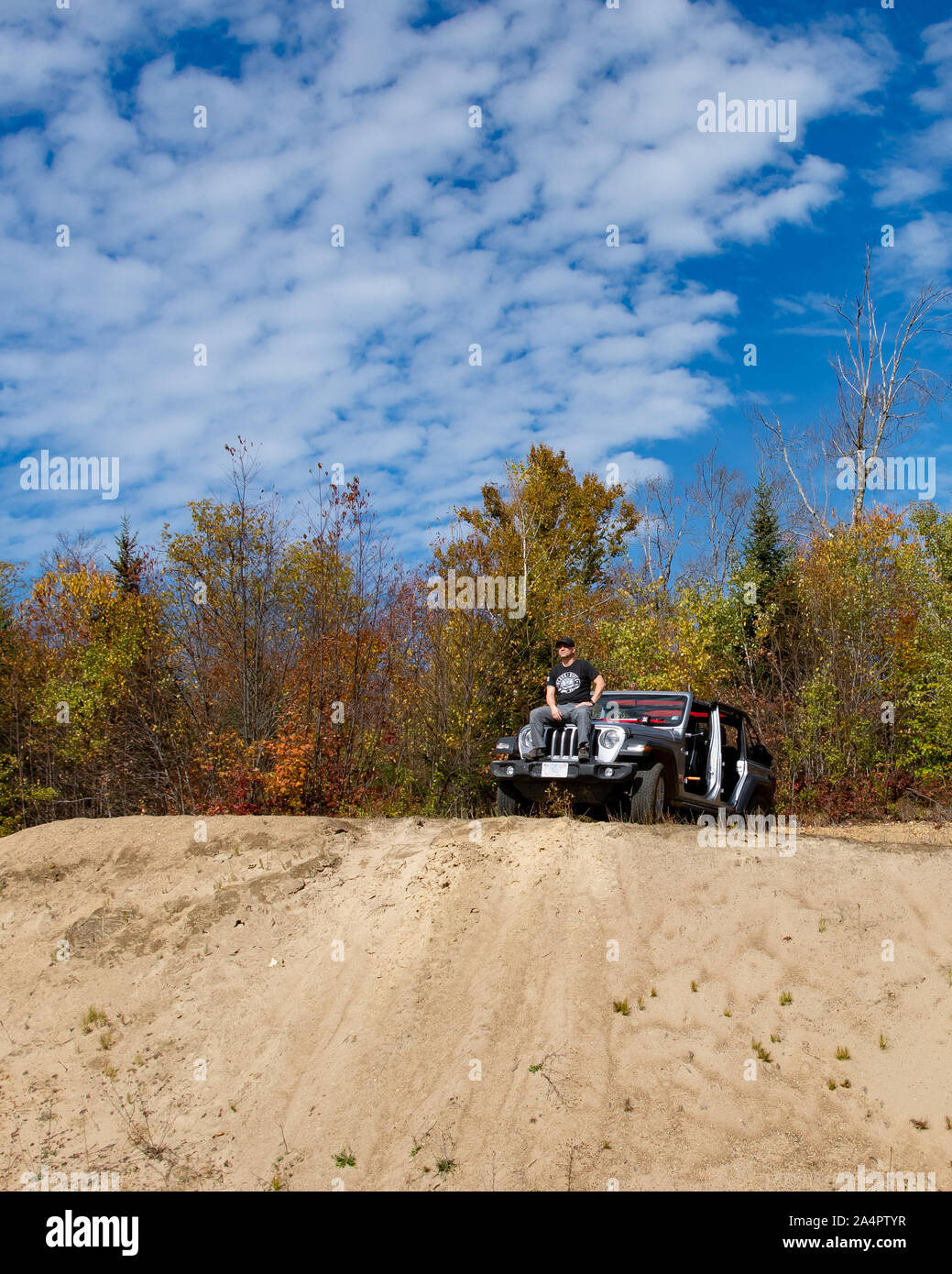 A Jeep Wrangler Unlimited without doors or a top parked on a sandy ridge in the Adirondack Mountains, NY USA on a clear sunny autumn afternoon. Stock Photo