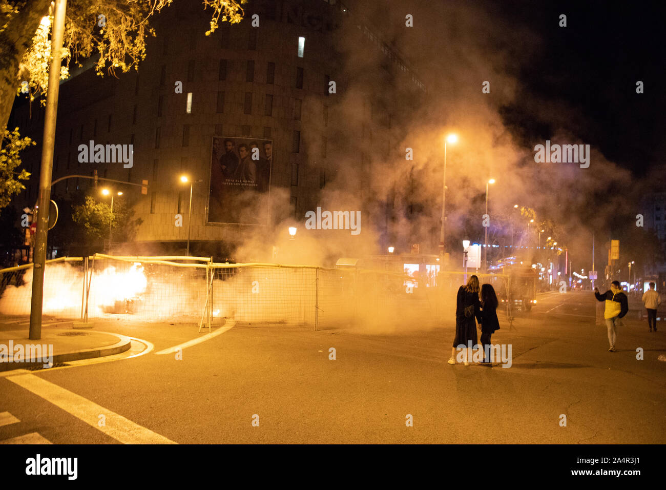 Barcelona, Spain - October 16, 2019:  People looking at the smoke on the main square of Barcelona after a fire has been  turned off. The fire was part of the protests again the prison sentence to catalan leaders for organizing the independence referendum and was aimed to block the main roads of Barcelona's cener Credit: Dino Geromella/Alamy Live News Stock Photo
