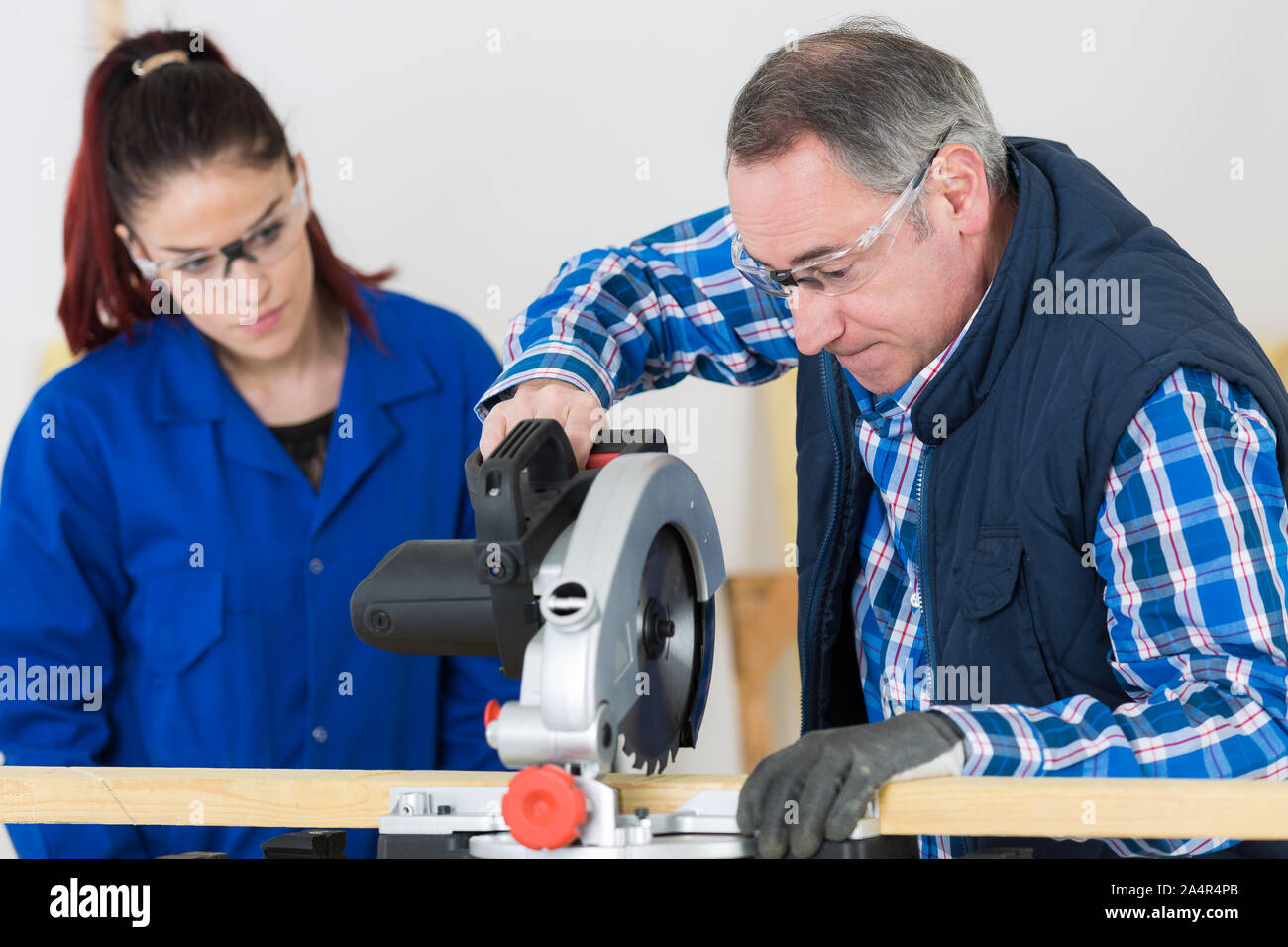 apprentice watching superisor used toothed circular saw Stock Photo