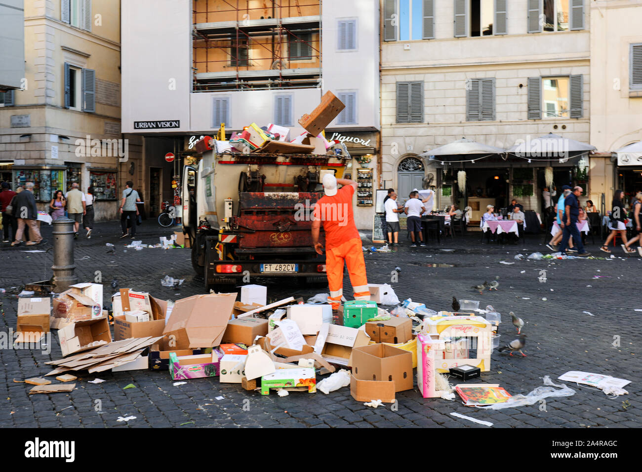 Sanitation worker throwing empty cardboard boxes to the small garbage truck at Campo de' Fiori market square in Rome, Italy Stock Photo