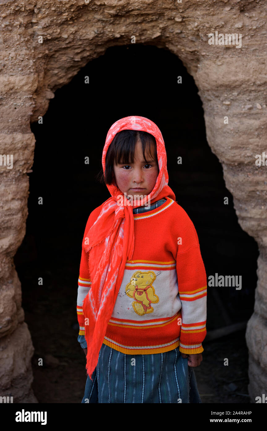 A young girl child stands at the entrance to a cave where her family keep cattle to keep them warm near her house, in the village of Rag-e-shad, on the outskirts of the city of Bamyan, in the central Bamyan Province, Afghanistan. May 11, 2009. Stock Photo