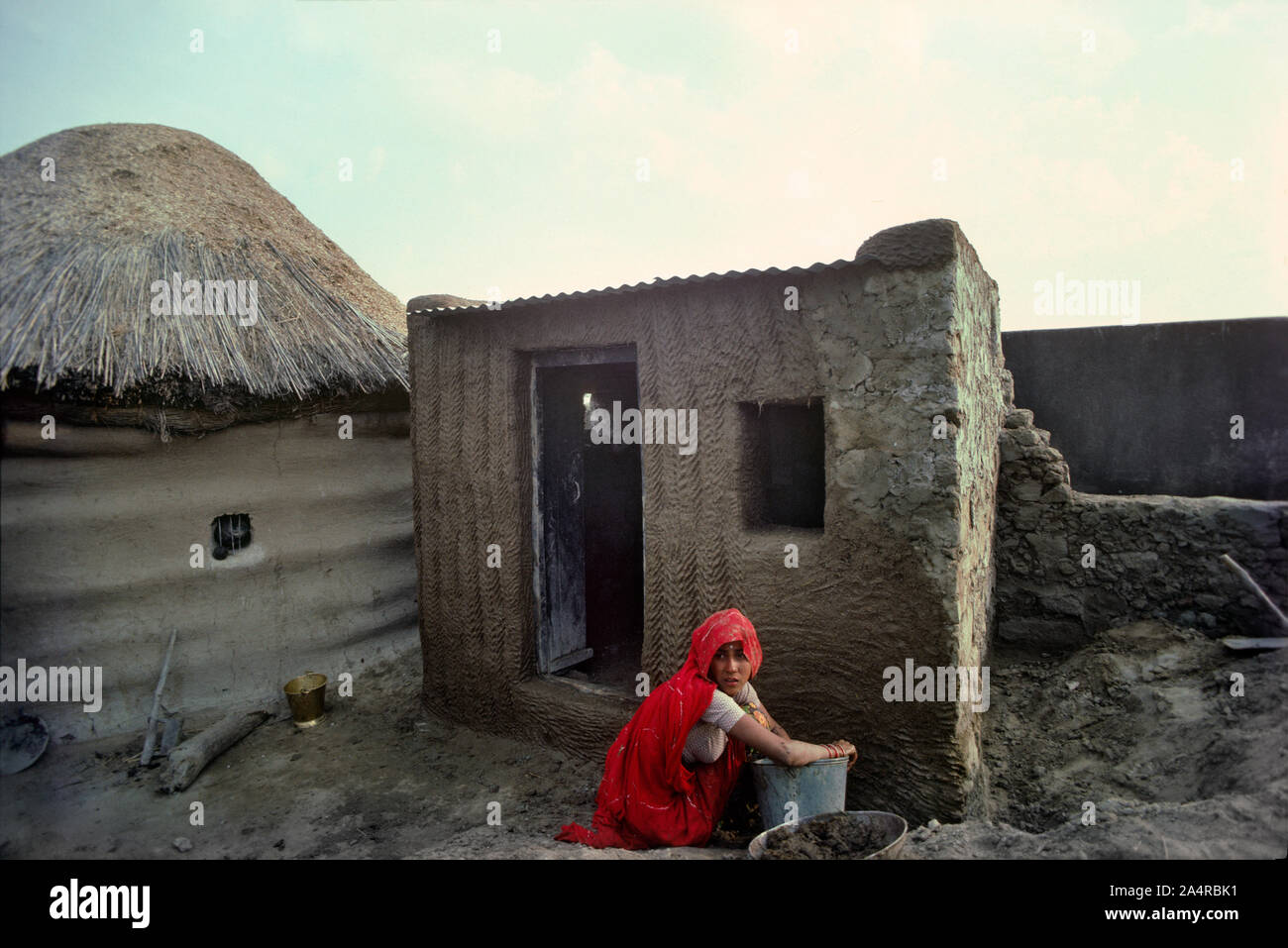 04 Mar 2020 woman applying Mud and cow dung plaster on house wall Sri Dungargarh Bikaner District Rajasthan India Stock Photo